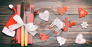 Top view of new year utensils on napkin with holiday decorations and reindeer on wooden background. Close up of christmas dinner