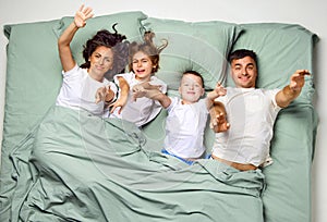 Top view of nice cute lovely attractive glad people covered with blanket lying in bed raising up arms to camera. Family