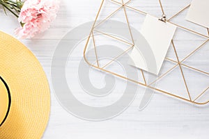 Top view note pad clip frame and summer yellow hat with pink flower on white wood table.summer vacation background