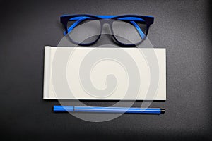 Top view note paper with blue eye glasses and blue pen