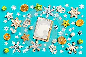 Top view of notebook on blue background with New Year toys and decorations. Christmas time concept