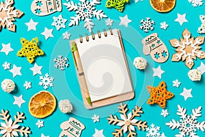 Top view of notebook on blue background with New Year toys and decorations. Christmas time concept