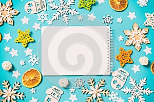 Top view of notebook on blue background with New Year toys and decorations. Christmas time concept