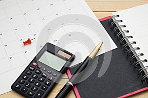 Top view notebook ,calculator,pen and calendar put on wooden flo