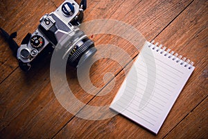 Top view of notebook paper and camera on Office desk table.