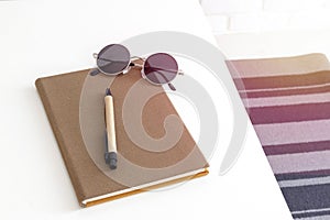 Top view of a notebook, pen and sunglasses