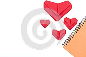 Top view Notebook,Red heart folded with paper origami hearts showing love for Valentine`s Day Isolated on White Background There