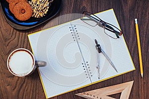 Top view of notebook, stationery, drawing tools and a few cups coffee.