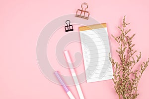 Top view of notebook stationery and flower on pink background