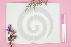 Top view of notebook stationery and flower on pink background