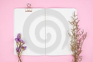 Top view of notebook stationery and flower on pink background