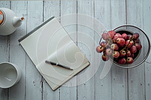 Top view notebook and Tea set, grape on wooden table