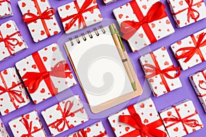 Top view of notebook, white gift boxes with red hearts on colorful background. Valentine`s Day concept