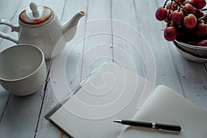 Top view Notebookâ€‹ andâ€‹ Tea set, grape on wooden table