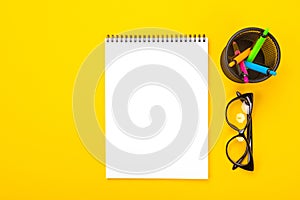 Top view of Notepad and glasses with glass with handles isolated on yellow background