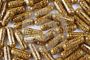 Top view of nutritional supplement capsules with bee pollen inside close up.