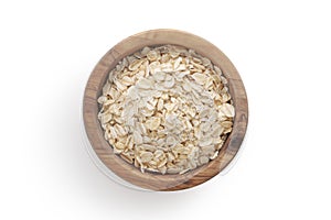 A top view of oat flakes in a wood bowl on white background