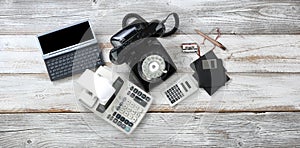 Top view of obsolete technologies that includes rotary dial phone and old computer data storage devices plus calculators