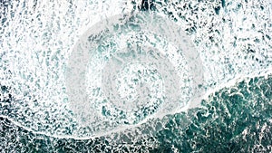 Top view of the ocean waves that crash against the rocky shore.