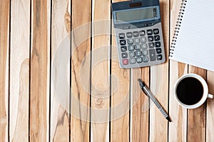 Top view Office desk with calculator, pen, blank notebook and coffee cup on wood table background. workspace or home office with