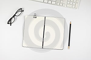 Top view of office desk with empty notebook and pencil