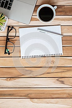 Top view Office desk with pen, computer laptop, blank notebook, plant pot and coffee cup on wood table background. workspace or