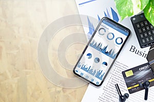 Top view of office desk table with business reports graph chart on mockup smartphone on businessman working desk table with copy