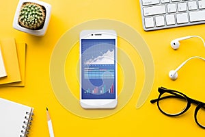 Top view of office desk table with graph chart on mock up smartphone photo