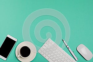 Top view of office desk workspace with smartphone, keyboard, coffee and mouse on blue background with copy space, graphic designer