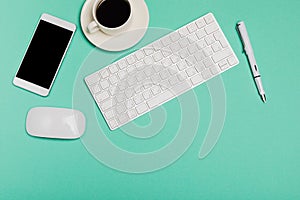 Top view of office desk workspace with smartphone, keyboard, coffee and mouse on blue background with copy space, graphic designer