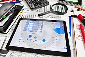 Top view of office employee`s desk - work with tablet pc computer and financial reports, analysis and accounting, tables and