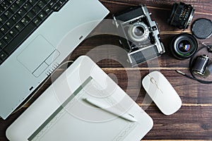Top view of office stuff graphic design pen mouse pad with laptop wireless mouse and vintage old camera on wooden table.Concept g