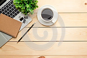 Top view office table desk. Workspace with blank, office supplies,Laptop, pencil, green leaf, and coffee cup on wood background
