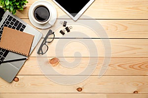 Top view office table desk. Workspace with blank, office supplies,Laptop, pencil, green leaf, and coffee cup on wood background