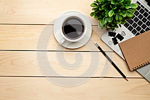 Top view office table desk. Workspace with blank, office supplies,Laptop, pencil, green leaf, and coffee cup on wood background