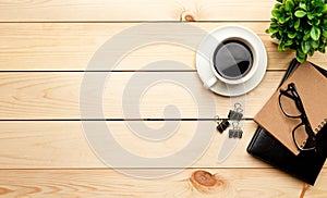 Top view office table desk. Workspace with blank, office supplies, pencil, green leaf, and coffee cup on wood background