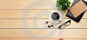 Top view office table desk. Workspace with blank, office supplies, pencil, green leaf, and coffee cup on wood background