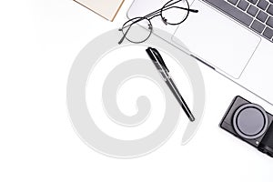 Top view office white table desk. Workspace with computer laptop, eyeglass, office supplies, and camera on white background