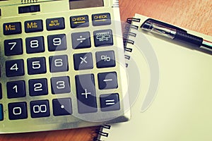 Top view of an office wooden desktop with calculator and pen