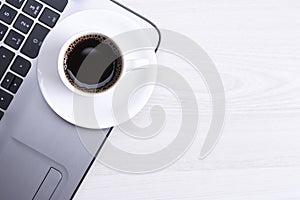 Top view of office work space, wooden desk table with laptop notebook,keyboard ,pen,eyeglasses,phone,notebook and cup of coffee.