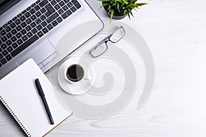 Top view of office work space, wooden desk table with laptop notebook,keyboard ,pen,eyeglasses,phone,notebook and cup of coffee.