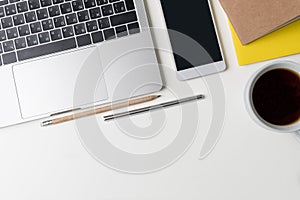 Top view of office workplace. White desk with copy space. Flat lay view on table with laptop, pen, phone, pencil, notebook