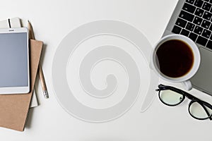 Top view of office workplace. White desk with copy space. Flat lay view on table with laptop, phone, notebooks, glasses