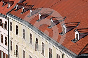 Top view of old building with red roof and windows on the roof. European city