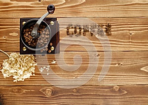 Top view of an old coffee mill and the word COFFEE written with coffee beans on a wooden surface