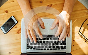 Top view of old man's hands on keyboard of lap top