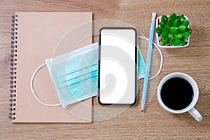 Top view of  old notebooks, anti-virus mask, smart phone, coffee cup on wooden table background. Work-life balance concept