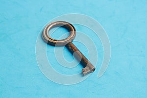 Top view of an old rusty key isolated on a blue background