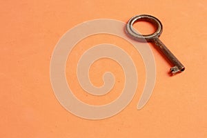 Top view of an old rusty key isolated on an orange background