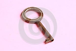 Top view of an old rusty key isolated on a pink background